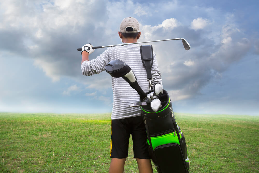 student holding golf caddy and club