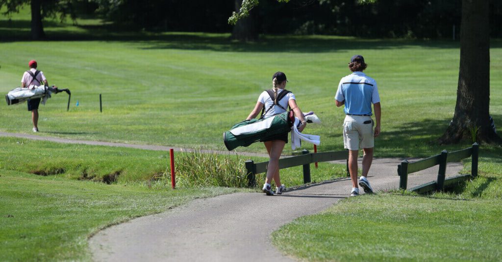 coach and student golfer walking down golf course
