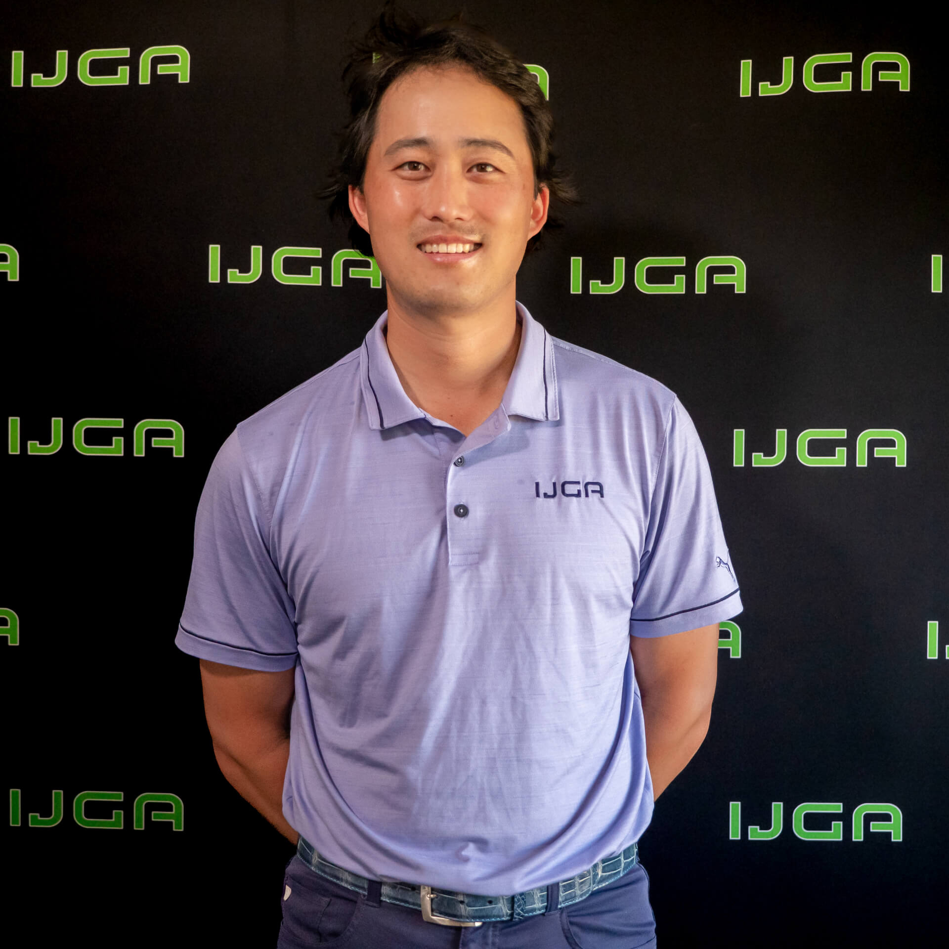 IJGA coach David Chong, smiles against a black IJGA logo background