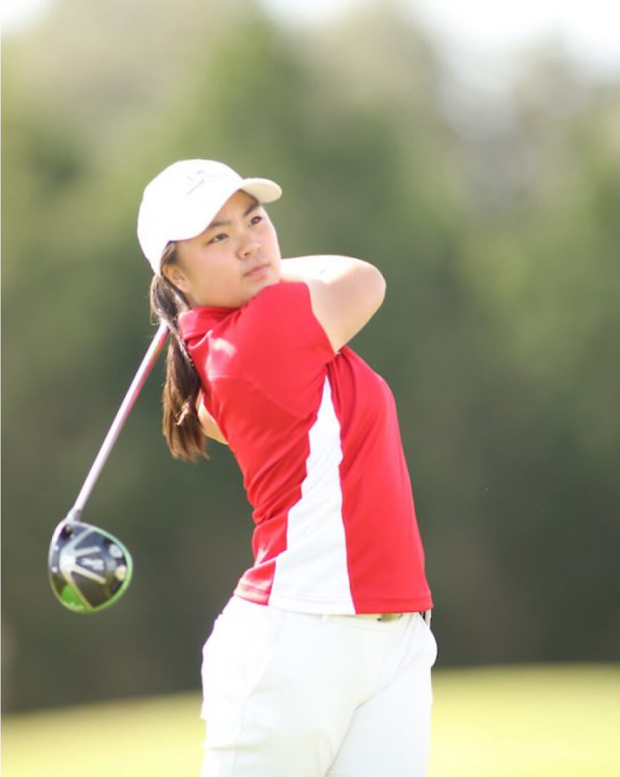 Golfer in red shirt finishes her swing