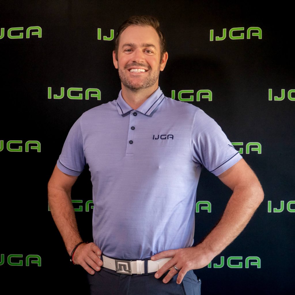 IJGA coach Grant Balcke, smiles against a black IJGA logo background