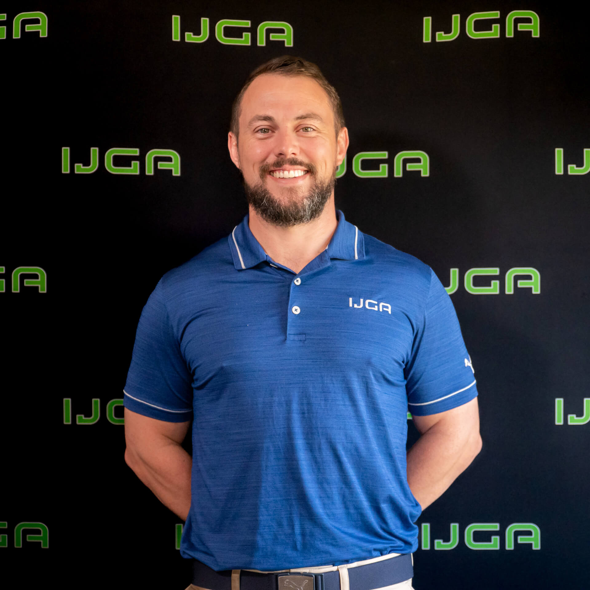 IJGA coach Sebastian Brown, smiles against a black IJGA logo background