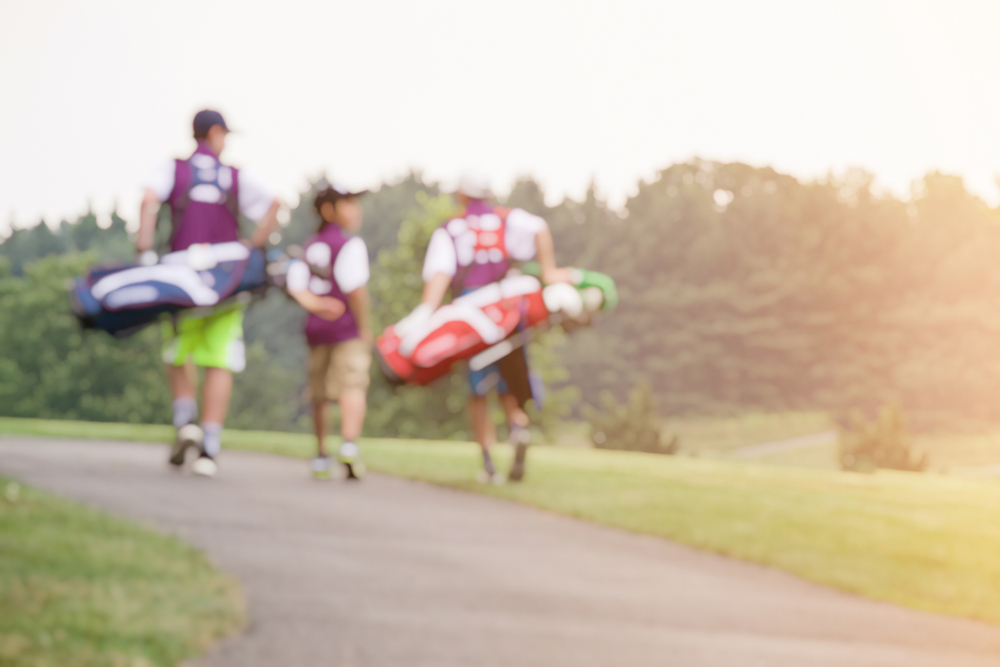 Junior golfers walk together and talk on the course