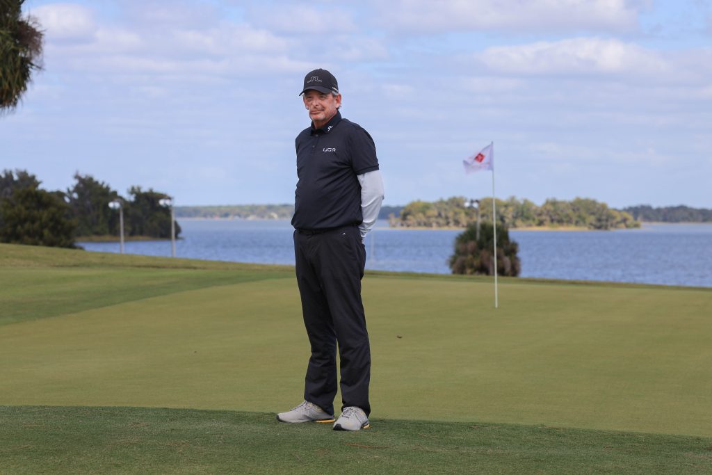 IJGA coach Hugh Royer, smiles against a black IJGA logo background