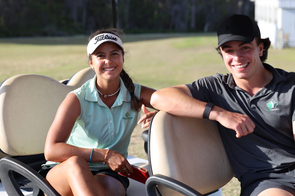 Two IJGA golfers smile in a golf cart.