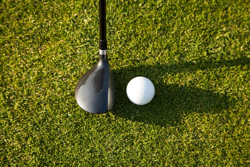 Golf club and golf ball on green grass