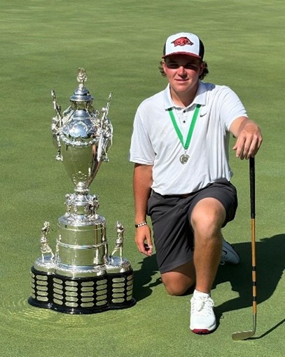 IJGA alumnus John Daly II kneels beside the Southern Amateur Championship trophy at Blessings Golf Club after securing victory for the University of Arkansas.